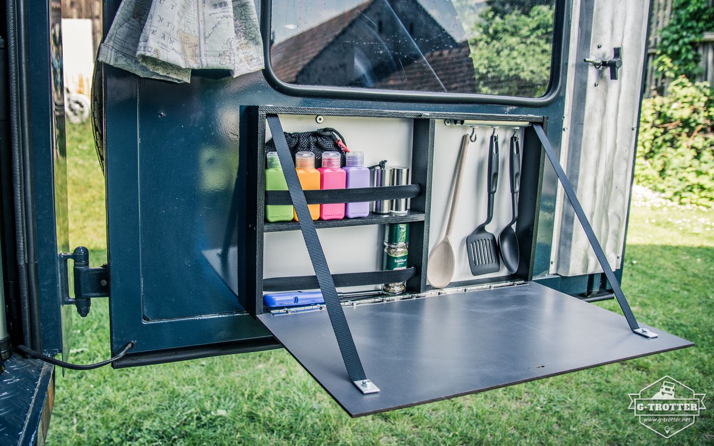 The box on the rear door with folded down lid. It serves as shelf for our Coleman stove and accommodates some kitchenware.