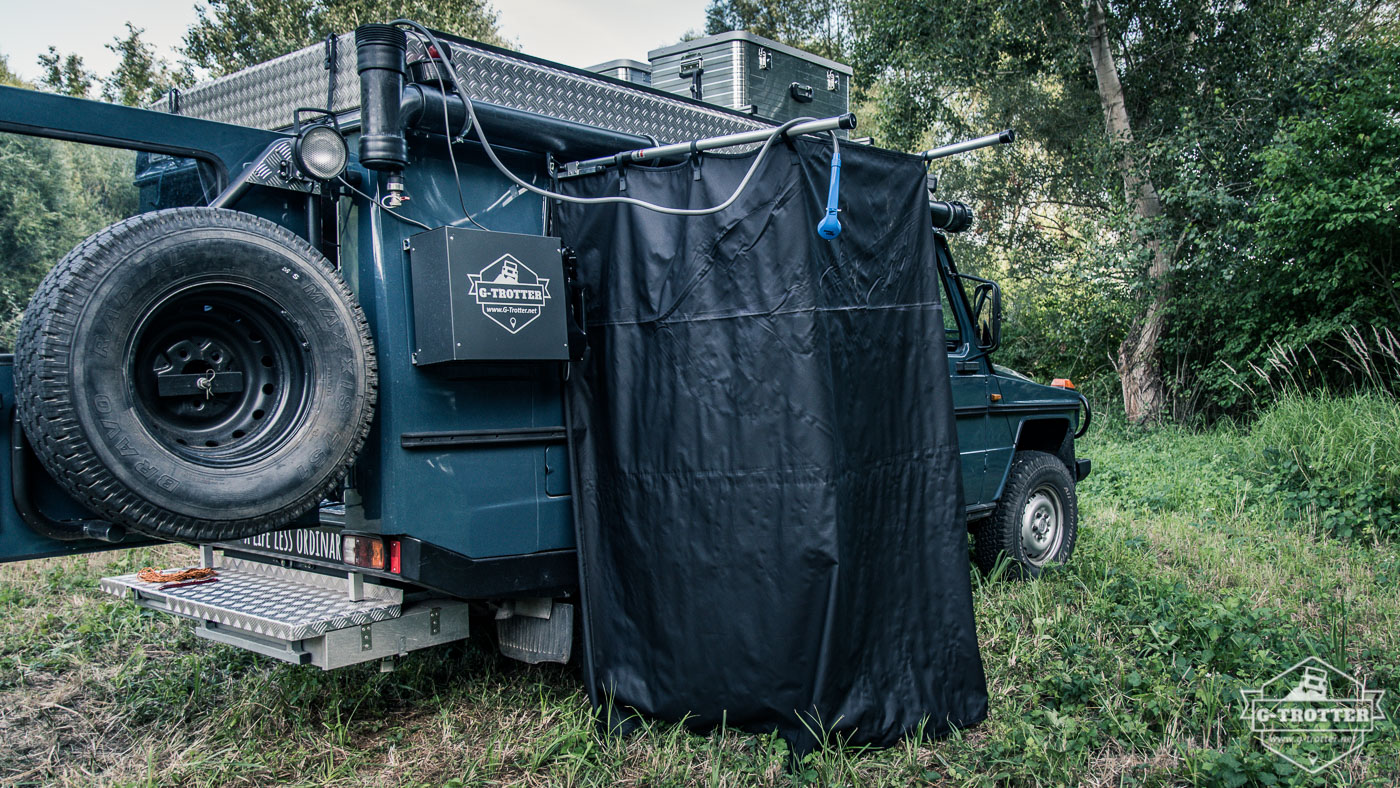 Die Tauchpumpe der Campingdusche wird in das schwarze Wasserrohr gehängt.